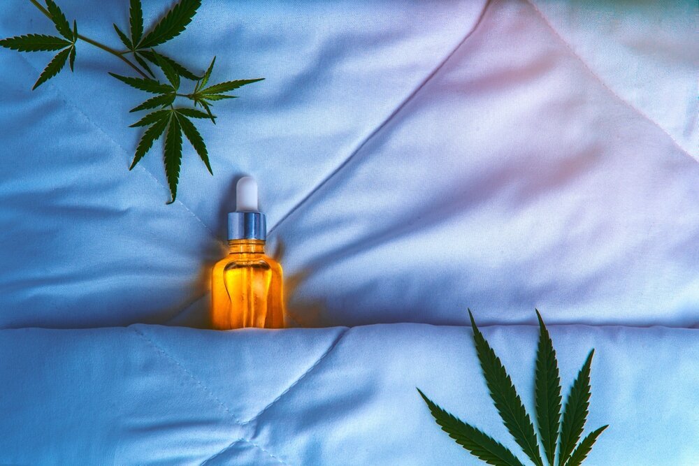 Cannabis and Sleep. Cbd Oil Tincture And Marijuana Leaf Under The covers.