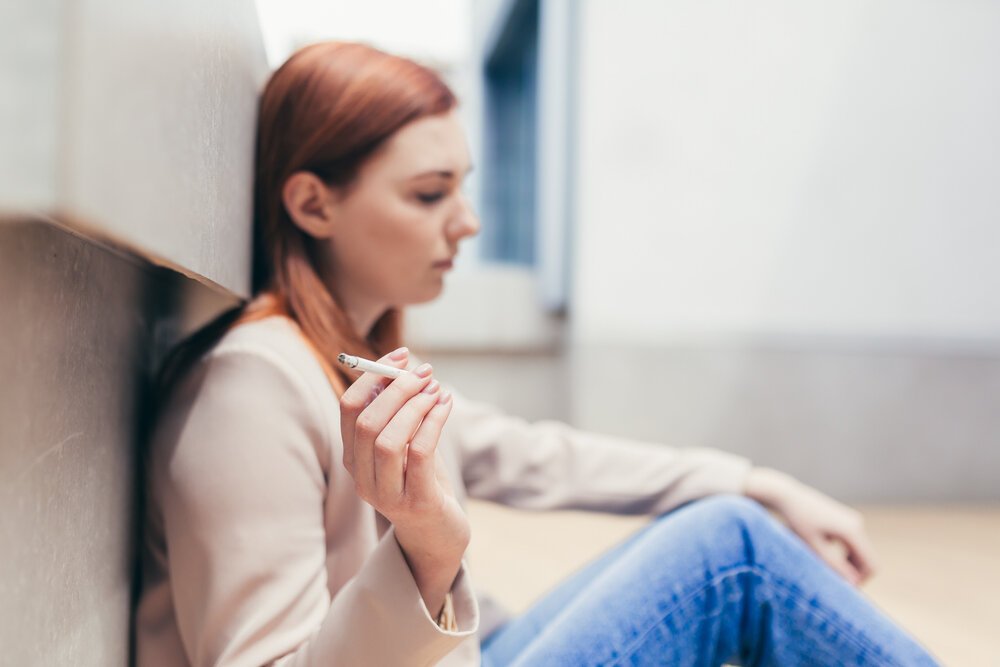 Cannabis for Managing Depression. Young Depressed Woman Sitting On The Street medicating with Cannabis.