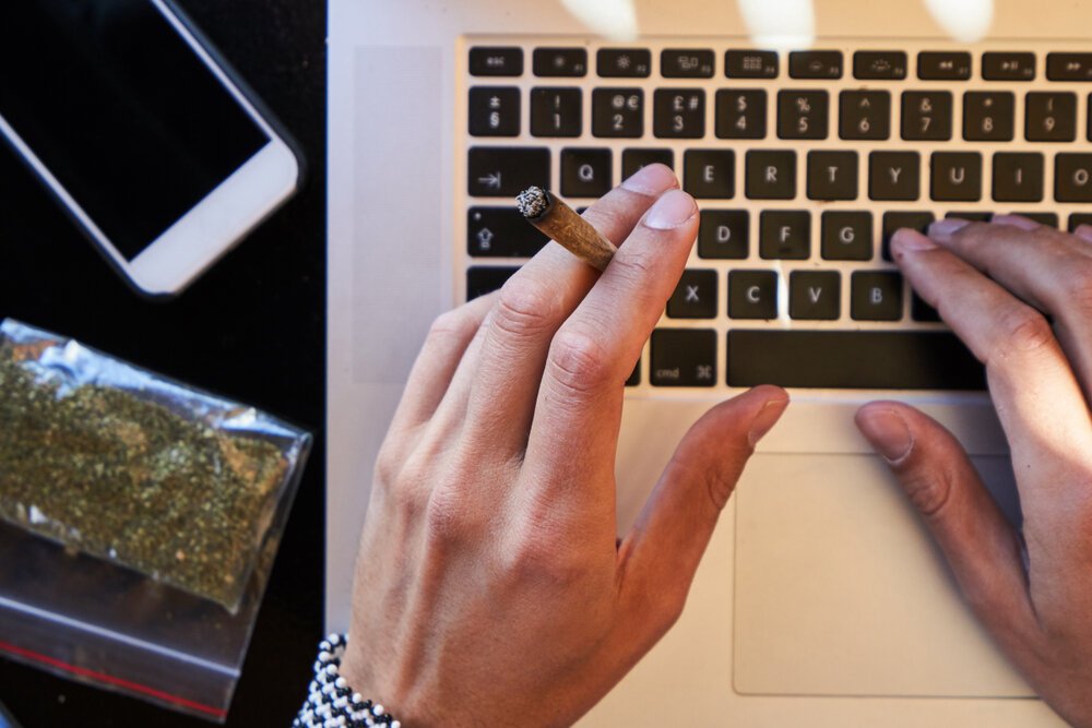 Cannabis in the Workplace. Close Up Top View Male Hand Holding A Joint Typing.
